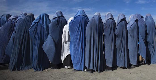 Afghan widows clad in burqas line up during a cash for work project by humanitarian organisation CARE International in Kabul January 6, 2010. In this project, 500 Afghan widows, most of whom lost their husbands during the civil wars in Afghanistan, make blankets after receiving the materials from CARE. REUTERS/Ahmad Masood (AFGHANISTAN - Tags: SOCIETY)